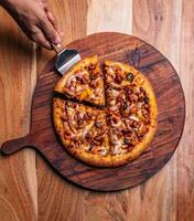 Pizza auf ein hölzern Tafel auf ein hölzern Hintergrund. oben Sicht. foto