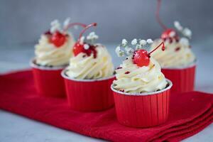 Cupcakes mit Kirsche auf ein rot Serviette auf ein Weiß Hintergrund foto