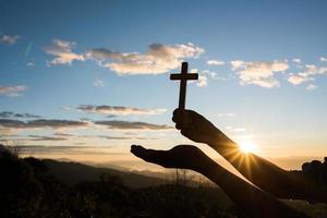 Silhouette der Hand halten das Kreuz Gottes foto