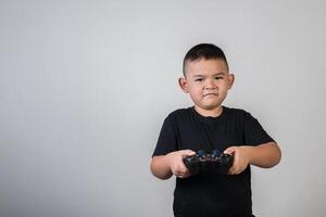 glücklicher Junge spielt Spielcomputer mit einem Controller im Studiofoto foto