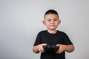 glücklicher Junge spielt Spielcomputer mit einem Controller im Studiofoto foto