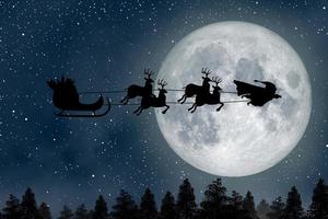 Super-Santa-Claus-Mann, ein Superheld, der über den Vollmond fliegt und seine Rentiere nachts zu Weihnachten führt. foto