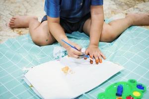 Konzentrieren Sie sich auf ihre Hände auf dem Papier. Kinder verwenden Pinsel, um ihre Hände auf Papier zu zeichnen, um ihre Vorstellungskraft zu fördern und ihre kognitiven Fähigkeiten zu verbessern.