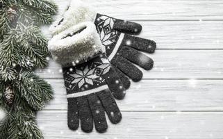 Winter-Strickhandschuhe auf Holzuntergrund in der Nähe von Tannenzweigen foto