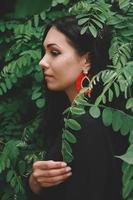 Frau im schwarzen Kleid und roten Dekorationen im Hintergrund des Waldes foto