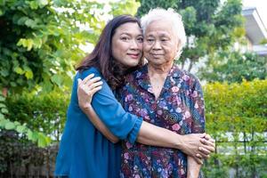 asiatische ältere frau mit pflegerin, die mit glücklich im naturpark spaziert. foto