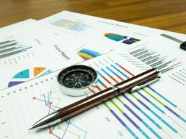 Geschäftsberichtsdiagramm und Finanzdiagrammanalyse mit Stift und Kompass auf dem Tisch foto