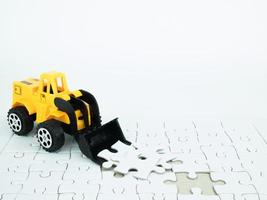 Spielzeug-Bulldozer mit Puzzle auf weißem Hintergrund foto