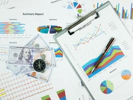 Geschäftsberichtsdiagramm und Finanzdiagrammanalyse mit Dollargeld, Stift und Kompass auf dem Tisch foto