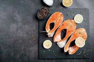 Anteil Fisch Forelle mit Zitrone und Gewürze auf dunkel Hintergrund foto