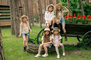 Gruppe Porträt von preteen Mädchen in der Nähe von alt hölzern Wagen benutzt wie Blume Bett im Park foto