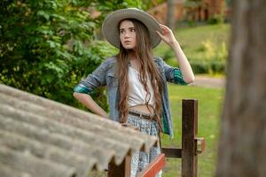 Teenager Brünette im Land Stil Kleider Stehen im Grün Hinterhof von Land Haus foto