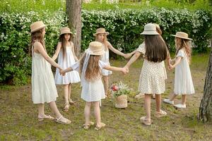 Gruppe von preteen Mädchen im Licht Kleider Tanzen im Kreis im Grün Sommer- Park foto