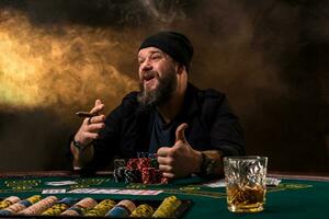 Mann ist spielen Poker mit ein Zigarre und ein Whiskey. ein Mann gewinnen alle das Chips auf das Tabelle mit dick Zigarette Rauch. foto