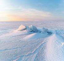 Winter Landschaft. Schneeverwehungen auf das Eis Oberfläche während Sonnenuntergang. foto