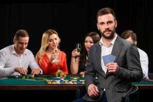 Poker Spieler im Kasino mit Karten und Chips auf schwarz Hintergrund foto