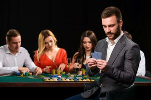 Poker Spieler im Kasino mit Karten und Chips auf schwarz Hintergrund foto