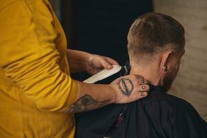 Friseur, der Haarschnitt des attraktiven bärtigen Mannes im Friseursalon macht foto