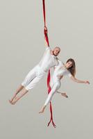 schön Mädchen und ein sportlich Mann im ein Weiß Sport Anzüge sind durchführen ein akrobatisch Elemente im ein Studio. foto