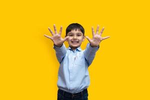 Porträt eines emotionalen, kaukasischen kleinen Jungen in einfacher Kleidung, der isoliert über einfarbigem Hintergrund genießt foto