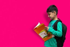 süßer 7-jähriger glücklicher Junge mit Schulrucksack, der Bücher im einfachen Hintergrund für Bildungskonzept hält foto