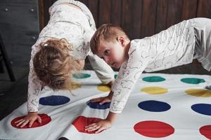zwei glückliche Kinder spielen im Twister im Haus. Bruder und Schwester haben eine lustige Zeit im Urlaub foto