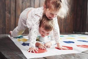 zwei glückliche Kinder spielen im Twister im Haus. Bruder und Schwester haben eine lustige Zeit im Urlaub foto