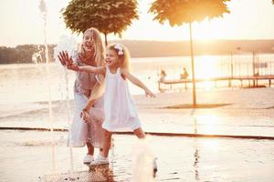 eine Frau, die bei Sonnenuntergang mit einem Kind am Meer im Park spielt foto