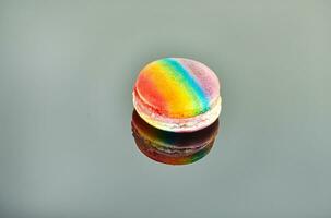 Nahansicht von ein köstlich und bunt regenbogenfarben Macaron platziert separat auf ein grau Oberfläche, Erstellen ein schön Betrachtung foto