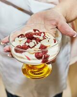 Koch vorbereiten Besondere Dessert mit frisch Creme, Kirsche, Kekse und Nüsse im ein Glas foto