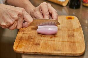 Schneiden frisch Schalotten auf hölzern Schneiden Tafel mit Küche Messer foto