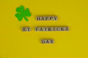 glücklich st. Patrick's Tag Wörter auf Gelb Hintergrund mit dreiblättrig Kleeblatt Blatt foto