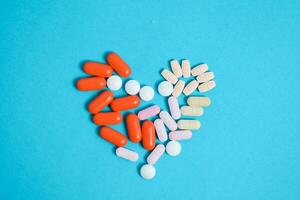 bunt Medizin Tabletten im Herz gestalten isoliert auf Blau Hintergrund, Ergänzung, Vitamin, bunt foto
