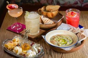 Essen Hummus, Gelee, verschiedene Käsesorten und Alkoholcocktails auf dem Tisch foto