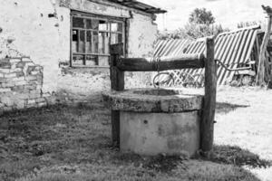 alter Brunnen mit Eiseneimer an langer geschmiedeter Kette für sauberes Trinkwasser foto