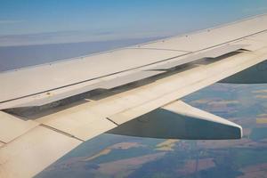 Flugzeugflügel mit offenem Spoiler am Himmel über Land foto