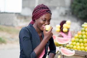 lächelnde junge Frau, die einen Apfel isst. foto