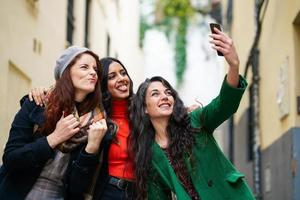 Gruppe von drei glücklichen Frauen, die zusammen draußen spazieren gehen foto