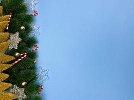 Weihnachtsschmuck, Kiefernblätter, goldene Kugeln, Schneeflocken, goldene Beeren auf blauem Hintergrund foto