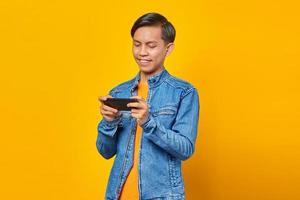 Porträt eines glücklichen jungen asiatischen Mannes, der ein Videospiel auf dem Handy spielt foto