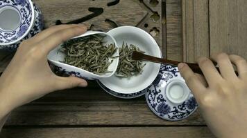Füllung ein braun Teekanne durch ein Trichter. Porzellan Chinesisch Tassen, Stahl Teelöffel. Schwarz, Grün, puerh, Oolong, Tieguanyin, Sencha, Tee foto