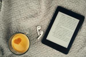 E-Book-Reader, eine Tasse Kaffee und ein Kopfhörer foto