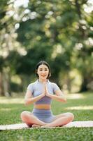 Porträt von jung Frau üben Yoga im garten.weiblich Glück. im das Park verschwommen Hintergrund. foto