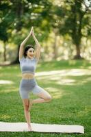 Porträt von jung Frau üben Yoga im garten.weiblich Glück. im das Park verschwommen Hintergrund. foto