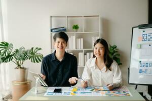 asiatisch Geschäftsmann und Frau Menschen Treffen im Büro. Mitarbeiter Brainstorming und Arbeit wie Team, planen und diskutieren Projekt durch Punkt auf Papier und Tablette. foto