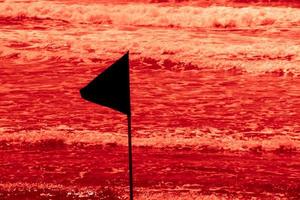 schwarze Warnflagge markiert die Grenze des sicheren Schwimmbereichs an einem wunderschönen Strand mit blauem Himmel und türkisfarbenem Meer in Israel foto