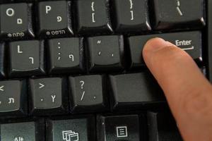 Mann tippt auf einer Tastatur mit Buchstaben in Hebräisch und Englisch foto