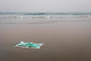 gebrauchte Mundschutz wurde an den Strand geworfen. Umwelt- und Ökosystemkonzept foto