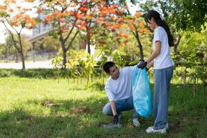 glücklich jung asiatisch Studenten vielfältig Freiwillige mit Müll Taschen Reinigung Bereich im das Park, das Konzept von Umwelt Erhaltung auf Welt Umgebung Tag, Recycling, Nächstenliebe zum Nachhaltigkeit. foto