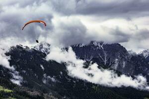 Gleitschirmfliegen im das Stubai Alpen unter wolkig Himmel foto